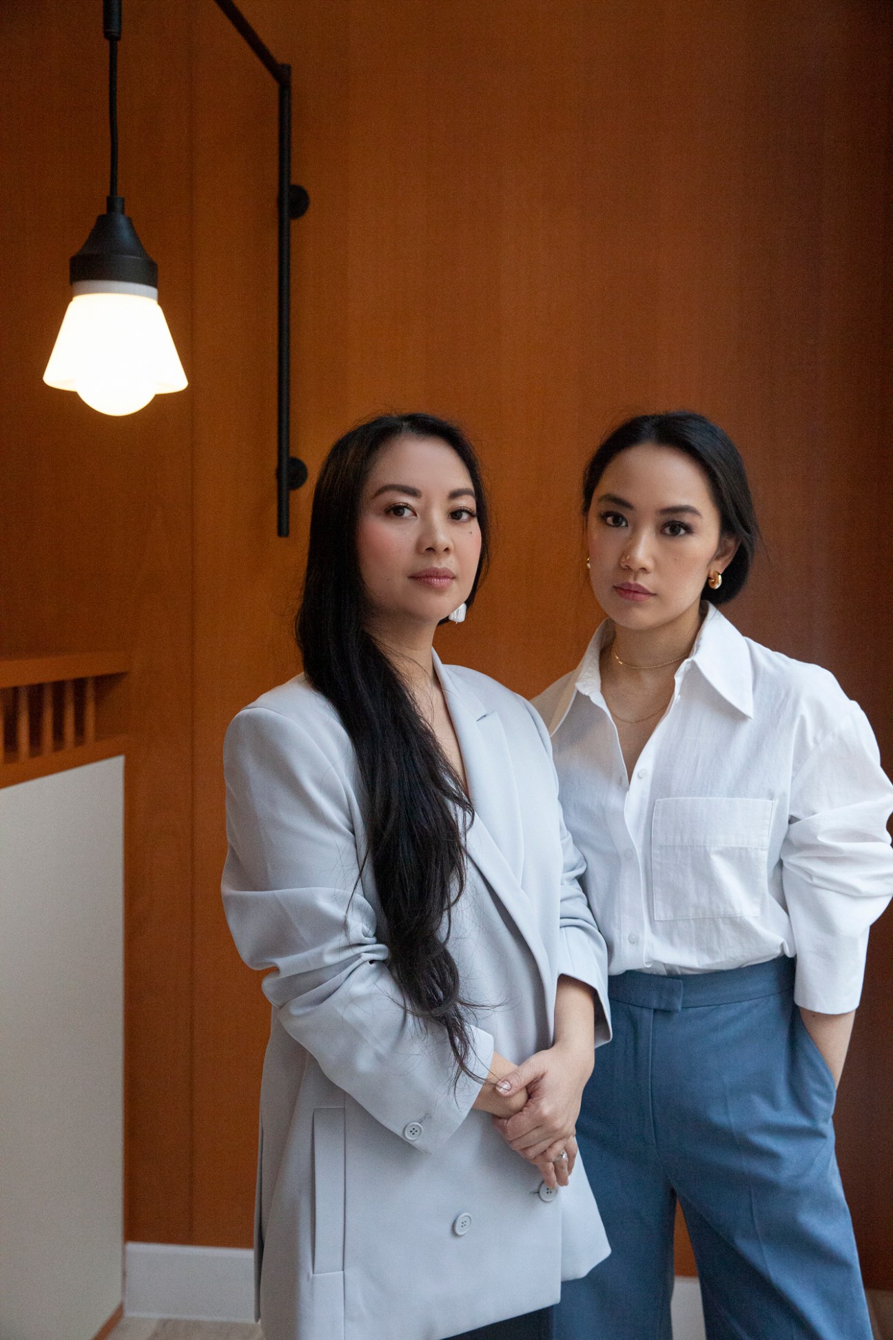 Two women in white business attire standing together in a modern restaurant interior
