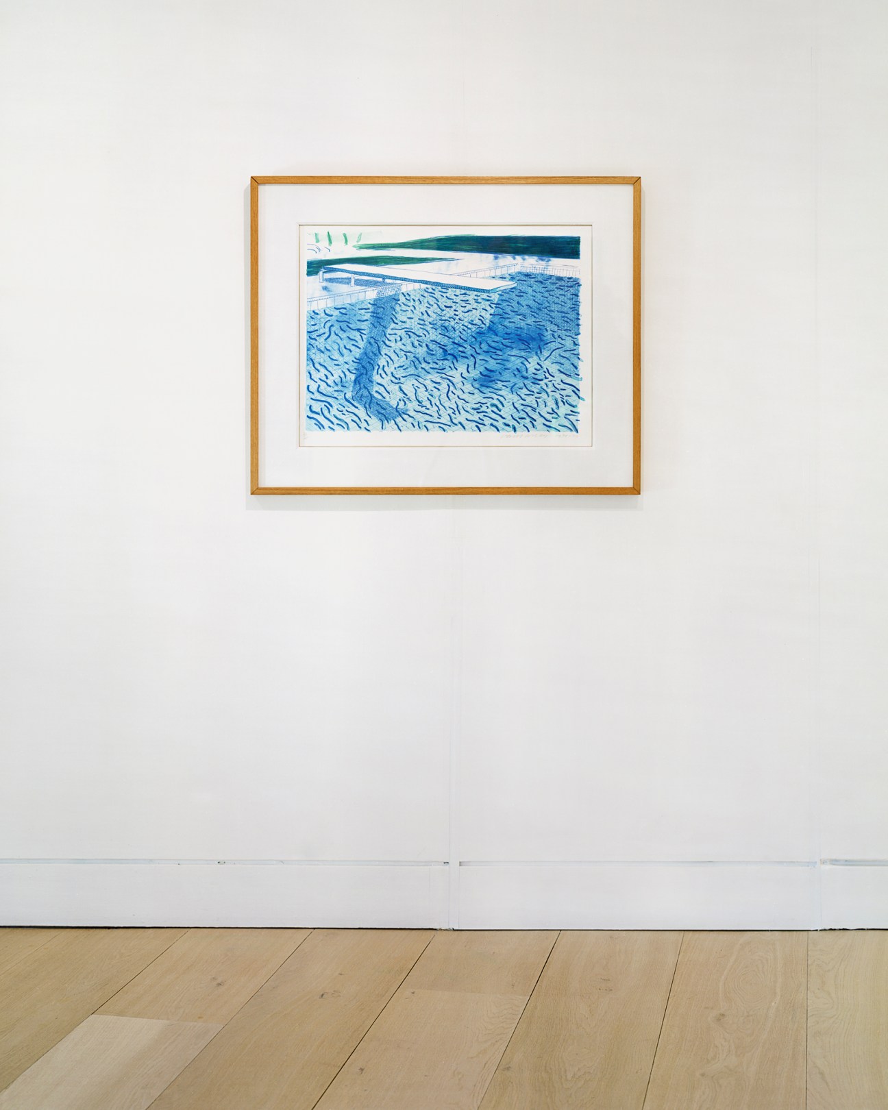 David Hockney lithograph showing abstract water patterns in blue tones displayed in gold frame on white wall