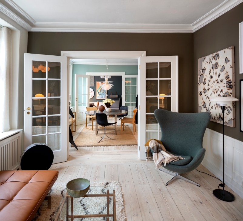 The Darling hotel's living room with mid-century modern furniture, contemporary art, and view through glass doors to the dining room.