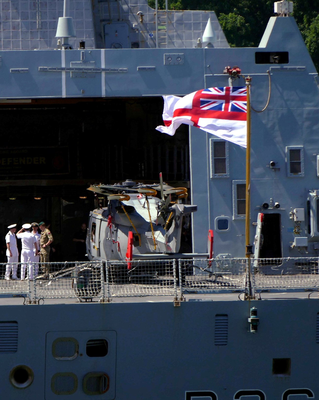 HMS Defender Royal Navy destroyer with Union Jack flag flying and crew members visible on deck