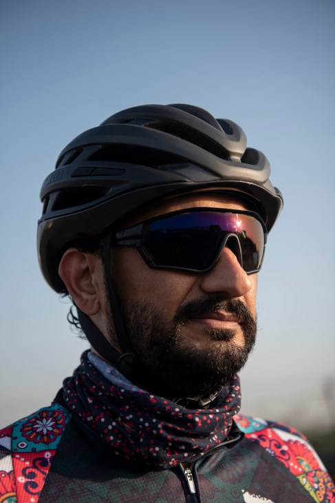 Praveen Kapoor wearing a black cycling helmet and mirrored sunglasses against a clear blue sky.