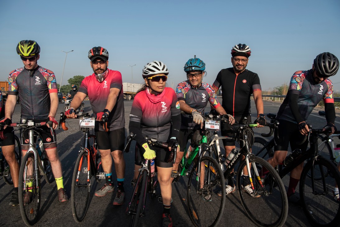 Reena Katyal and fellow Delhi Cyclists members stand with their bikes on a New Delhi highway, wearing helmets and cycling gear.
