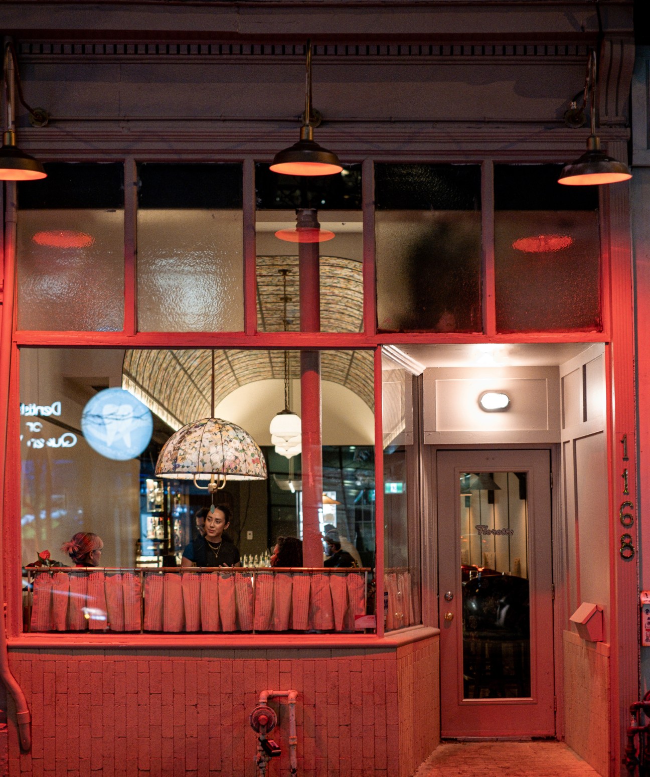 Red-framed storefront of Florette restaurant in Toronto with large windows showing interior dining space and staff