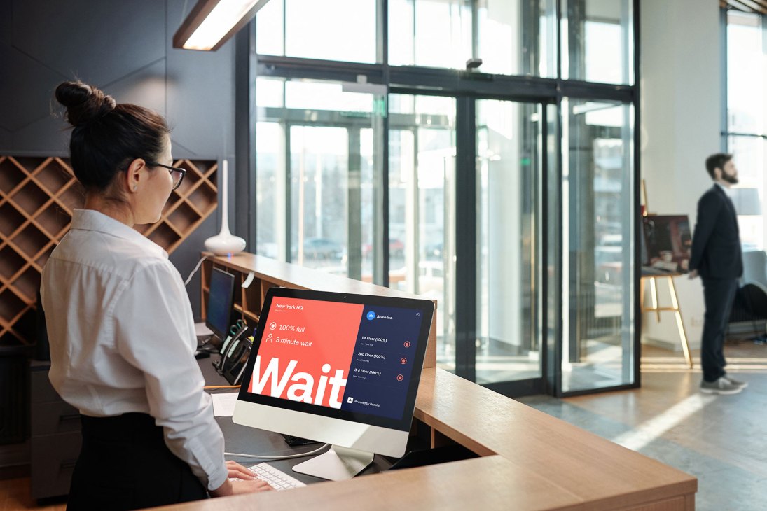 Woman at computer workstation viewing Density software displaying wait times and occupancy data