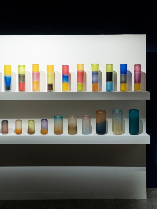 Colorful glass vessels and vases displayed on white shelves