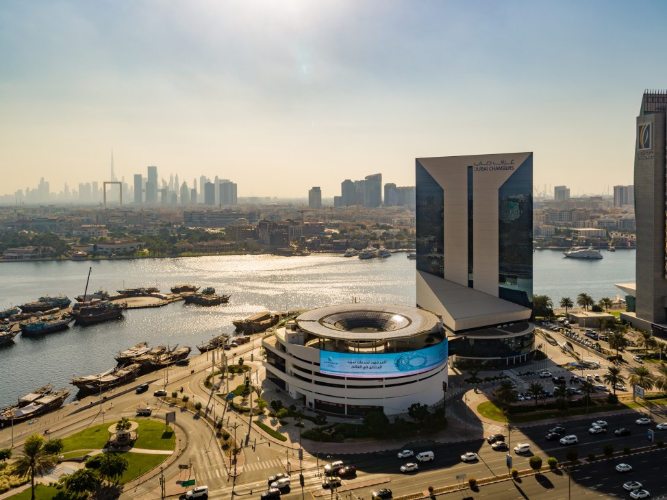 Aerial view of Dubai Chamber of Commerce Building by Dubai Creek with dhows and skyline.