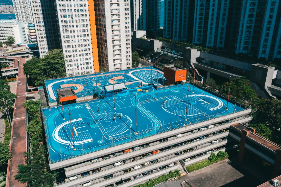 Aerial view of blue rooftop basketball courts and recreational facilities surrounded by high-rise residential buildings