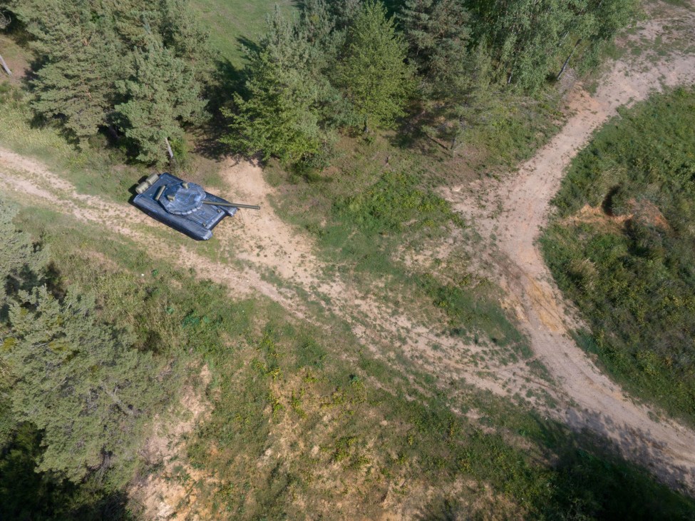 Aerial view of an inflatable military tank decoy positioned on terrain among forested areas