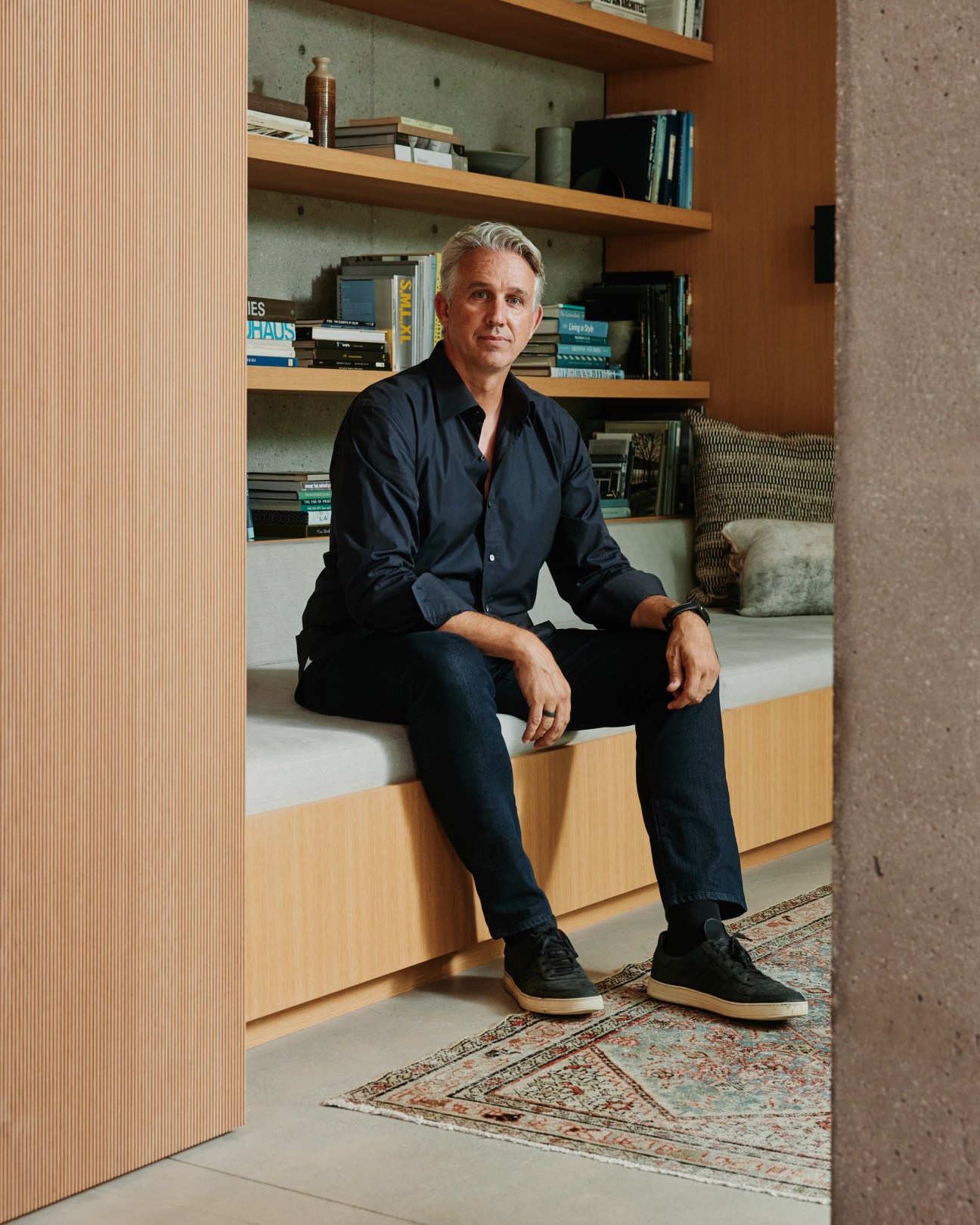 Architect David Montalba sitting in modern interior with built-in seating and bookshelves