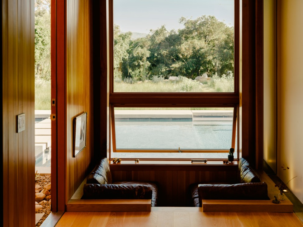 Interior alcove with built-in wooden bench seating and large windows overlooking water and trees