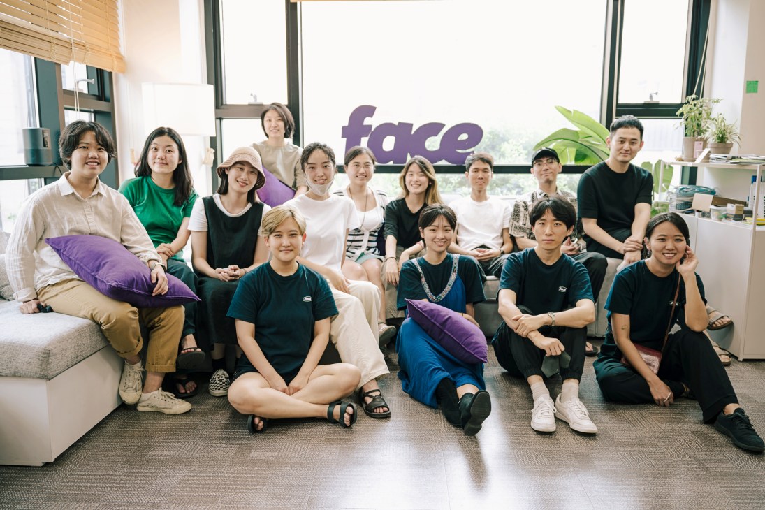 Dotface team members posing together in a bright Seoul office with the company's purple logo visible on the wall.