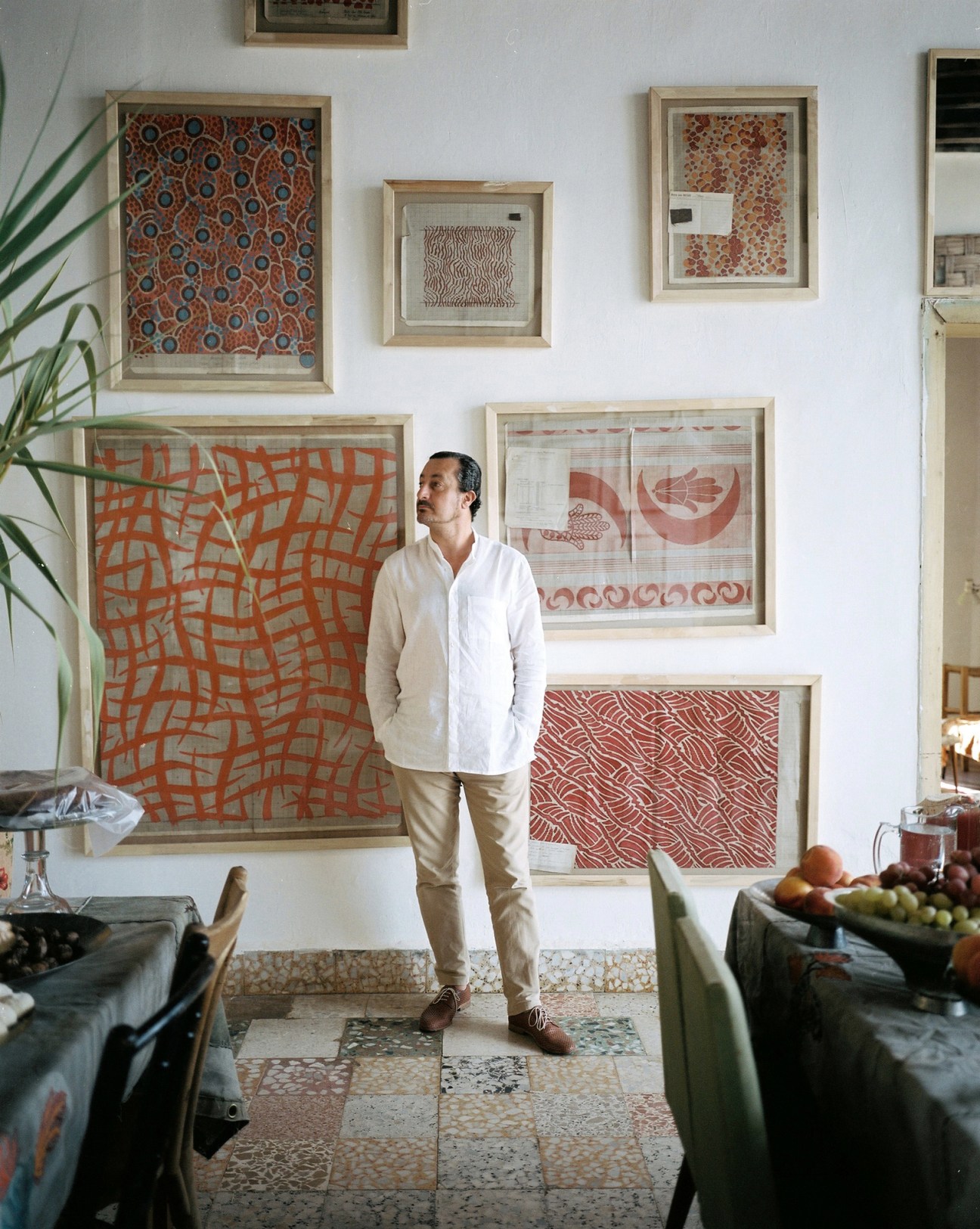 Owner Kamal Mouzawak standing in his traditional Lebanese stone house surrounded by framed artwork