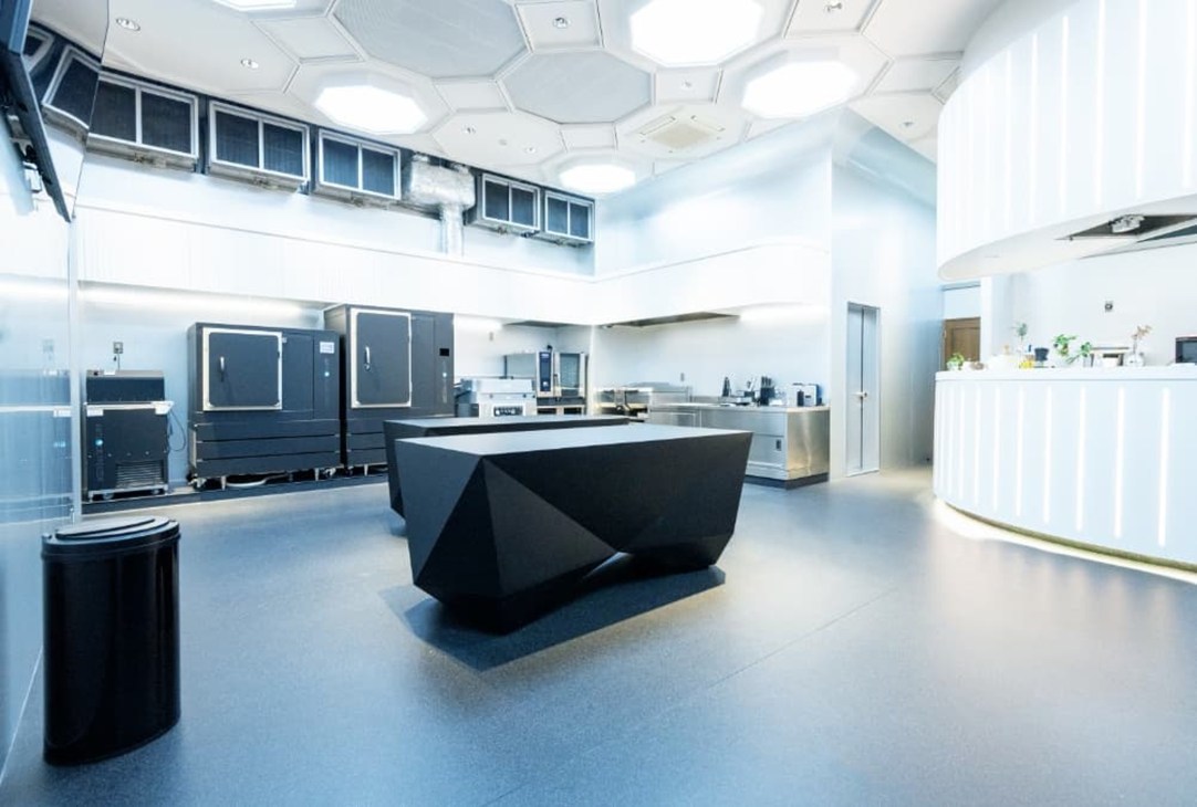 Modern laboratory with hexagonal ceiling panels, black geometric equipment, and sterile white surfaces