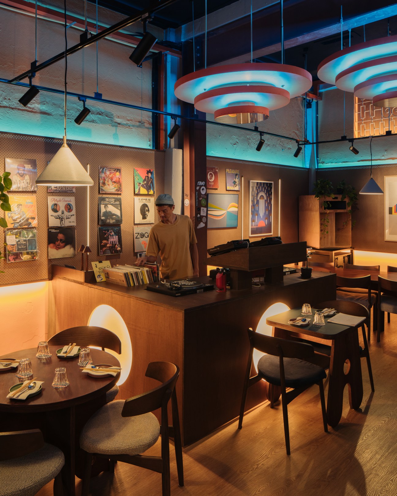 Interior of Offtrack listening bar with DJ at turntables, vintage audio equipment, vinyl records and dining tables