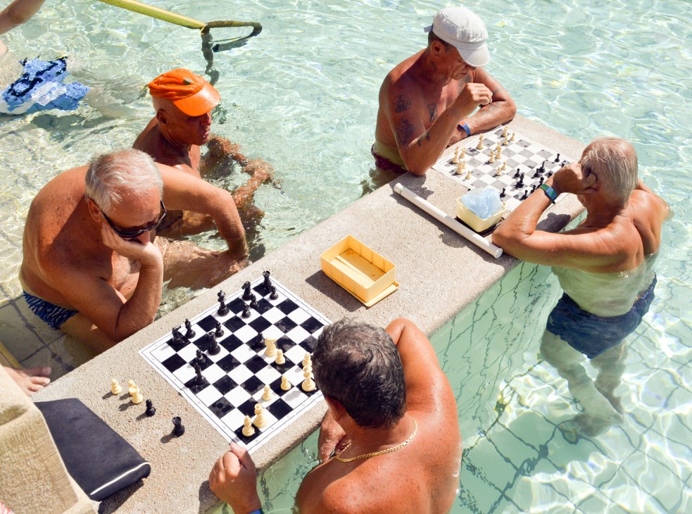 Men playing chess while relaxing in thermal bath pools in Budapest