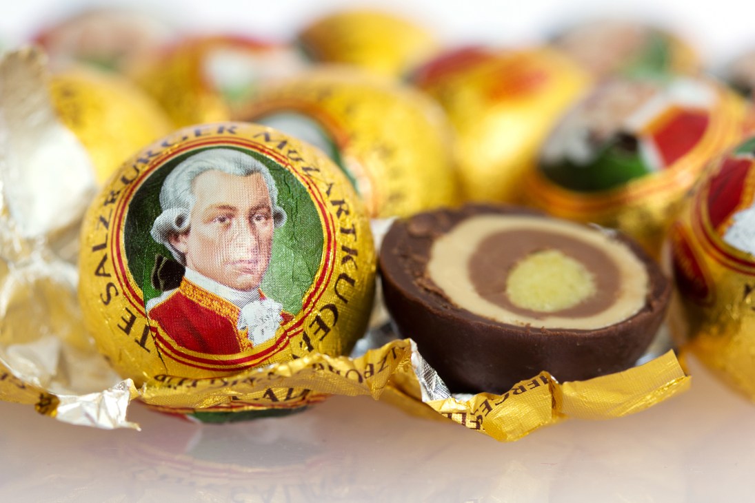 Mozartkugeln chocolate balls with portrait of Mozart on golden wrapper, one unwrapped showing chocolate layers