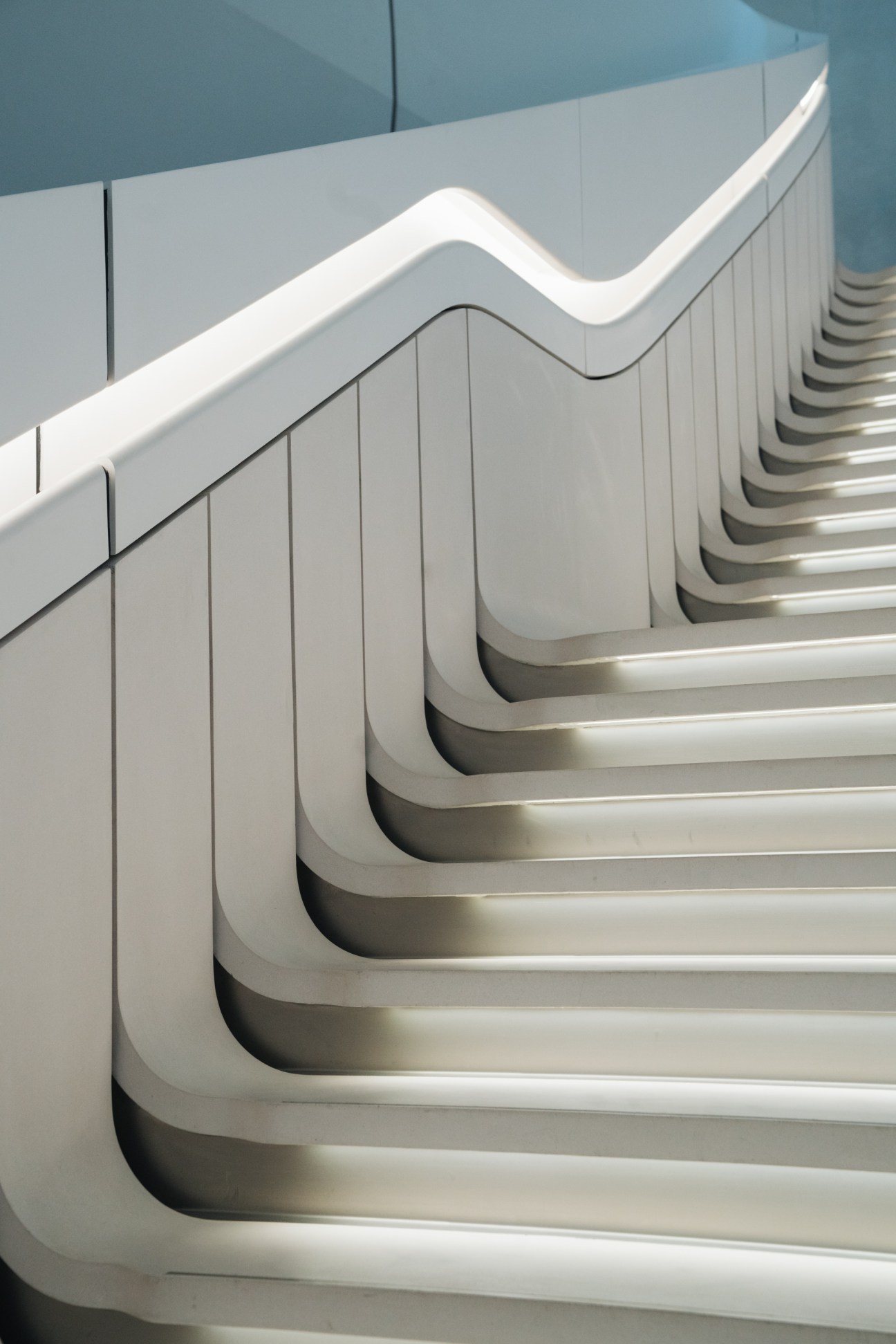 White curved staircase with undulating handrail and steps creating flowing architectural lines.