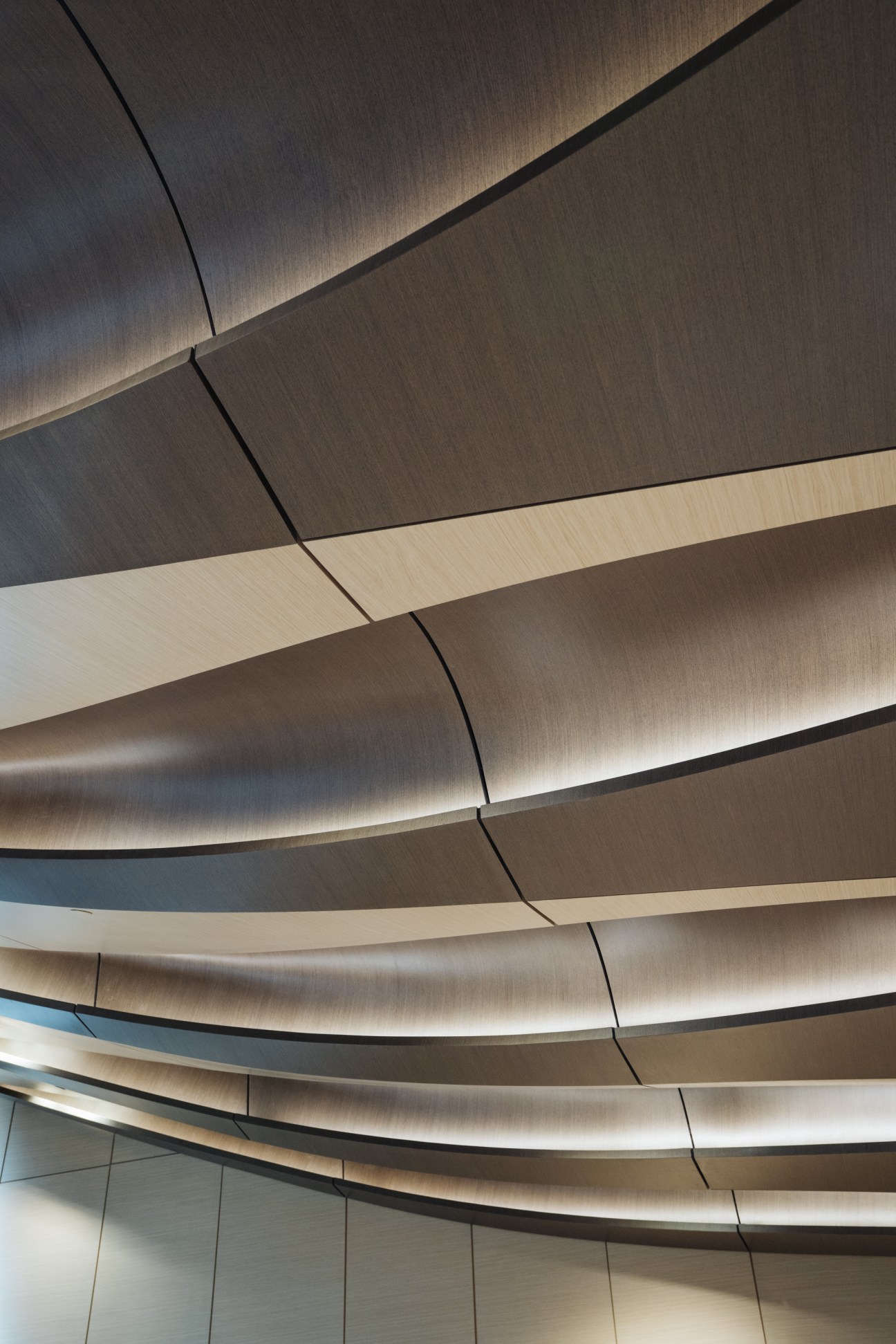 Undulating curved ceiling of Beeah HQ with alternating light and dark bands creating dune-like contours.