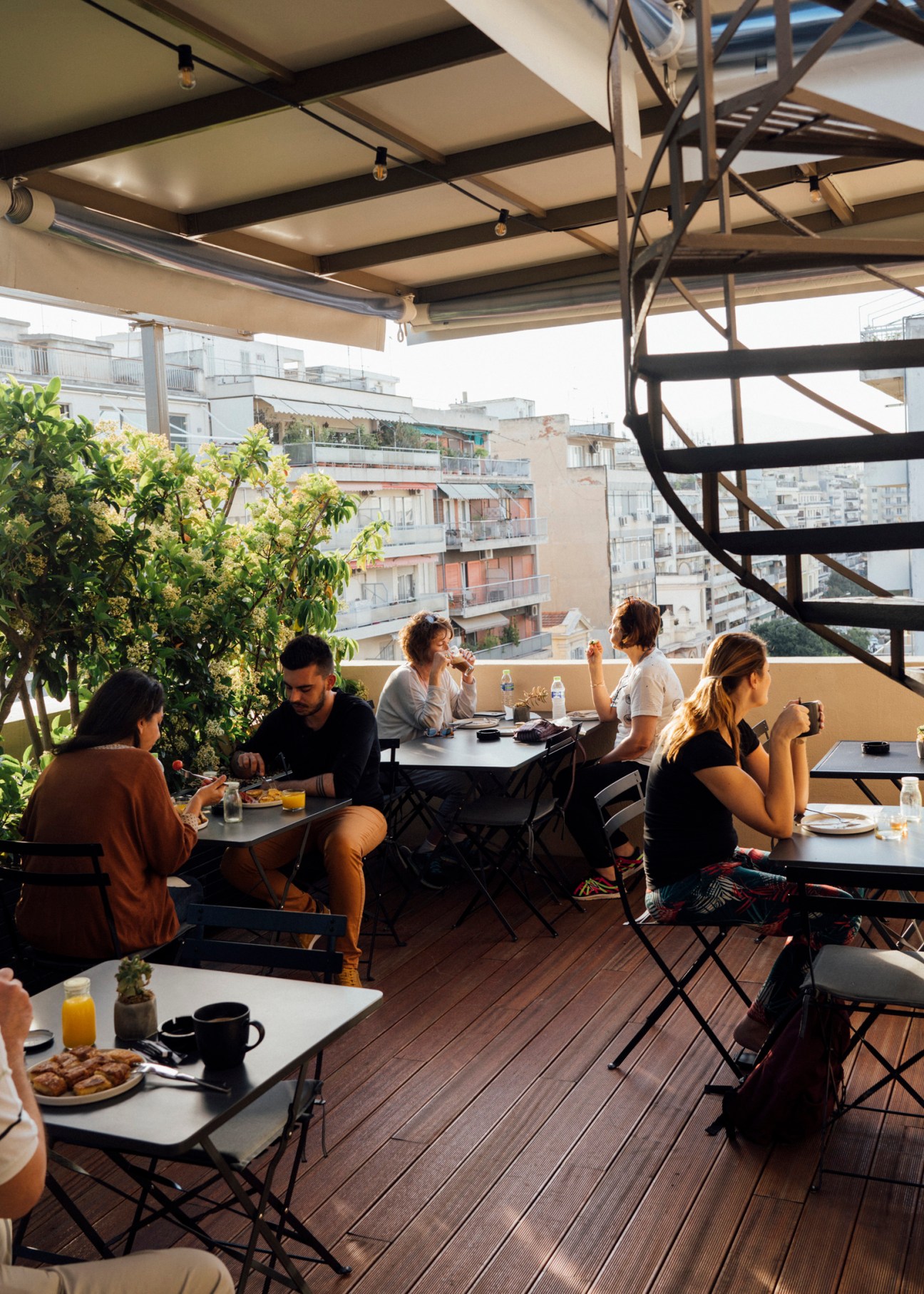 People dining on a shaded rooftop terrace with city views at The Modernist hotel in Thessaloniki.