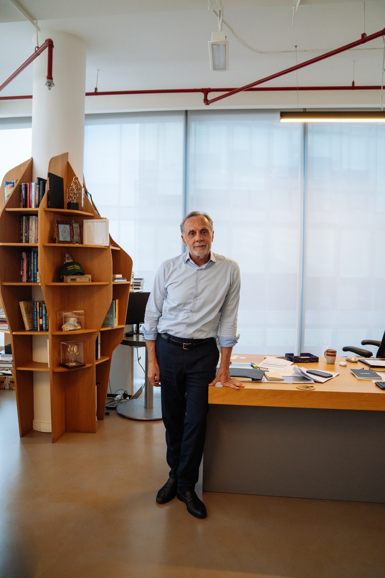 Fadi Ghandour, chairman of Wamda Capital and co-founder of Aramex, stands in his office beside a wooden sculptural bookshelf.