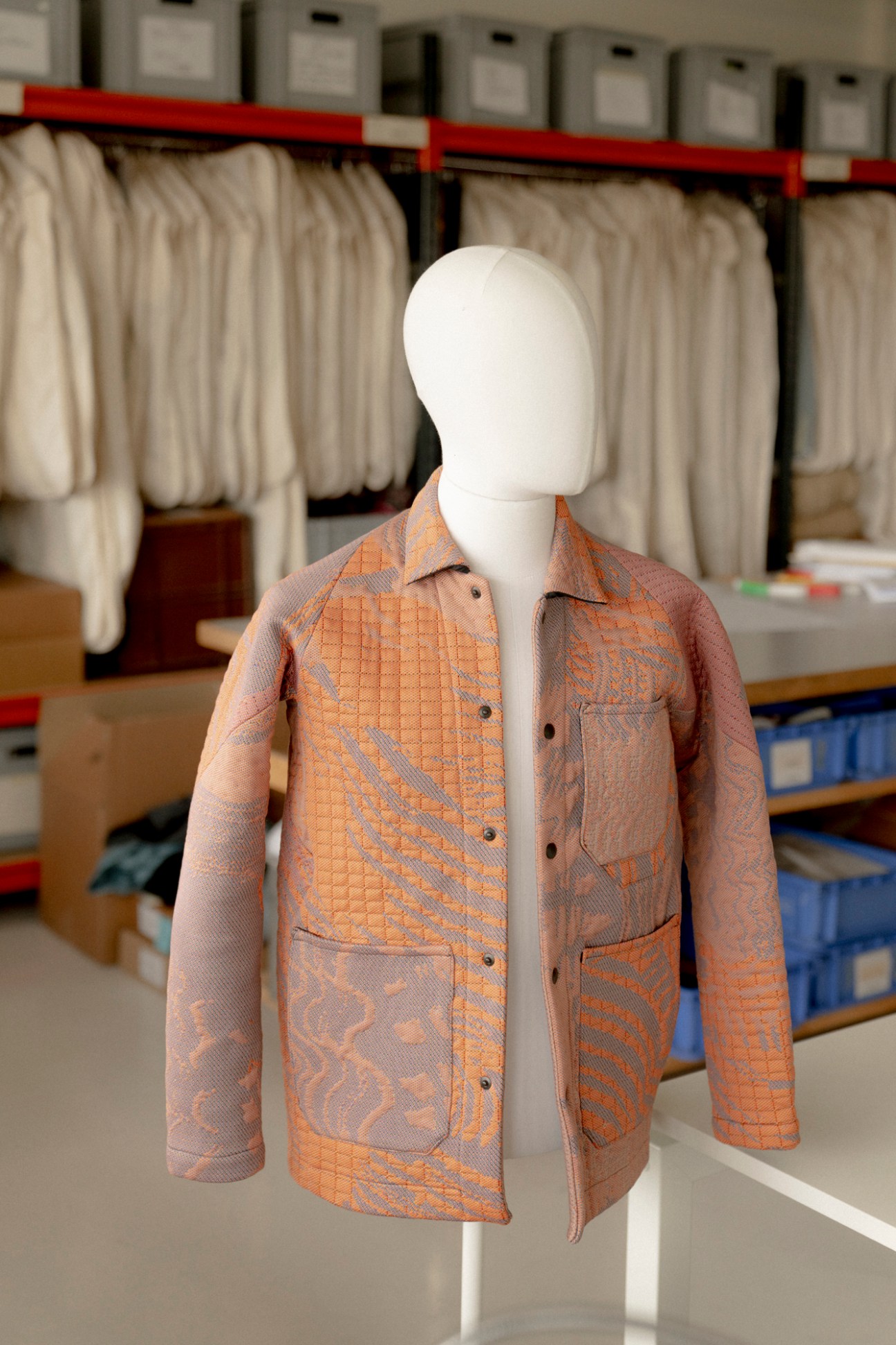 Byborre jacket displayed on white mannequin in showroom with clothing racks in background