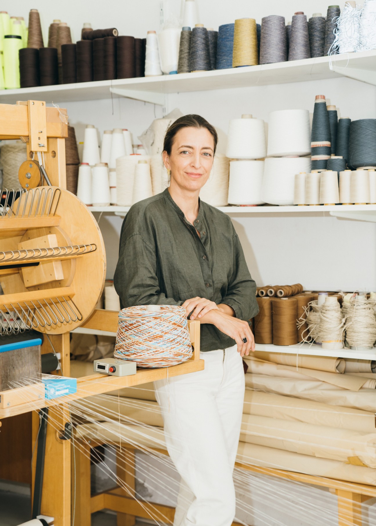 Textile designer Joanna Louca working at her wooden loom in her bright whitewashed studio