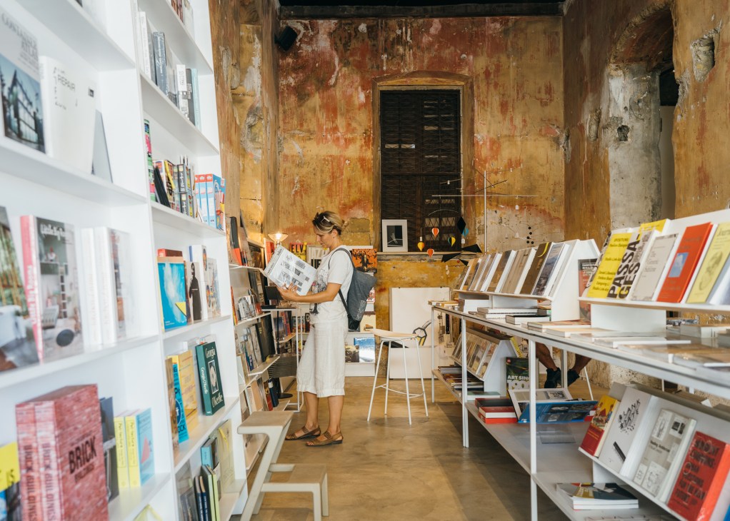 Person browsing books at Meres bookshop in Nicosia, examining design and architecture titles on white shelves