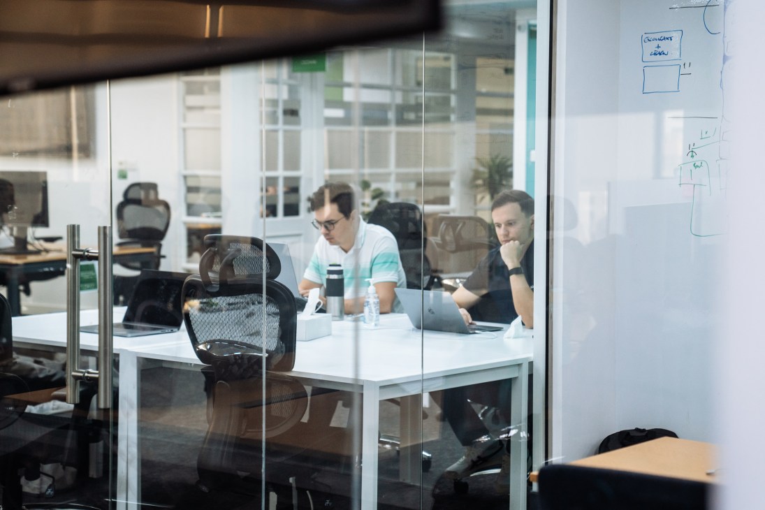 Three employees work at a table inside a glass-walled office at Careem's headquarters.