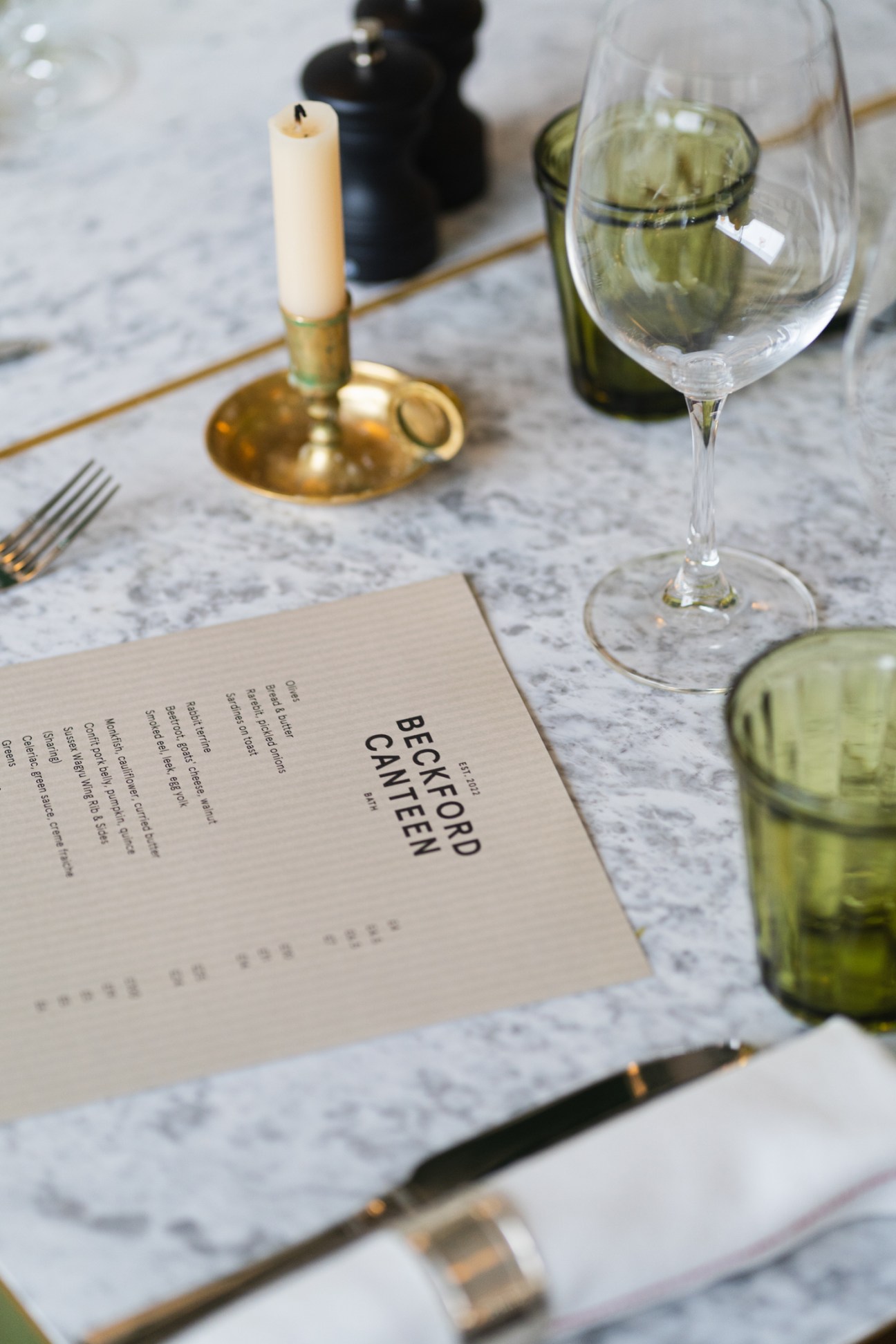 Fine dining table setting with menu, wine glasses, candle and place settings at Beckford Canteen.