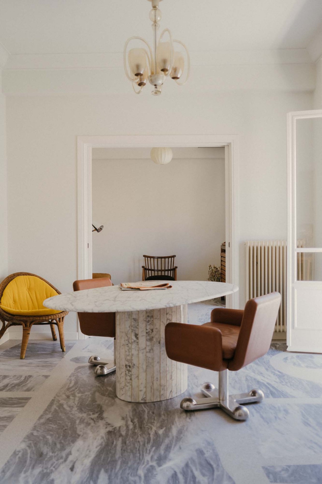 Modern dining room with marble table and vintage chairs including a yellow seat by Ettore Sottsass