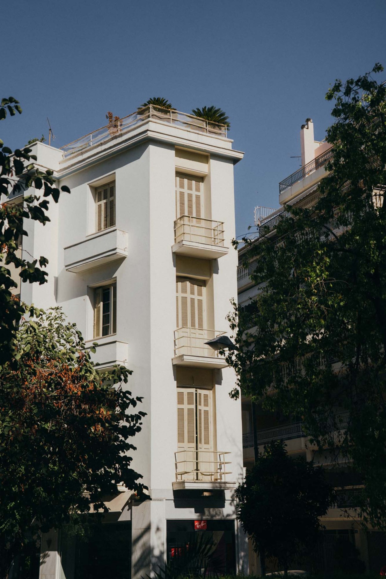 Mid-century polykatoikia apartment building in Athens with white facade and green shutters