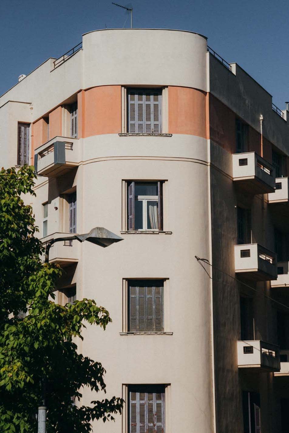 Mid-century polykatoikia apartment building with curved balconies and orange-painted section in Athens