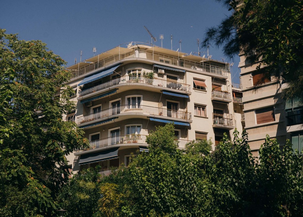 Mid-century polykatoikia apartment building with curved balconies surrounded by greenery in Athens