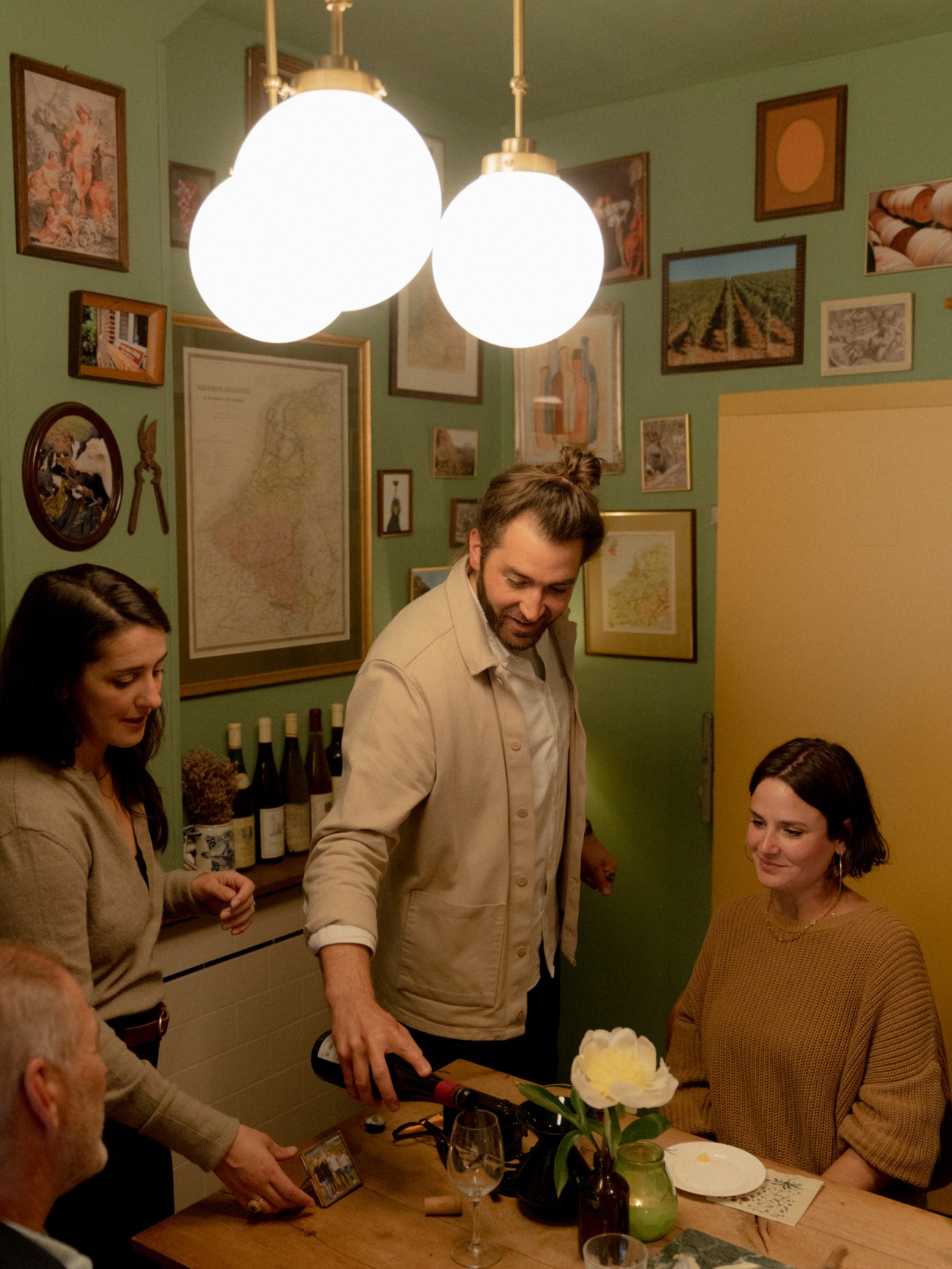 Wine and cheese tasting in an intimate dining room with art-covered walls and pendant lighting