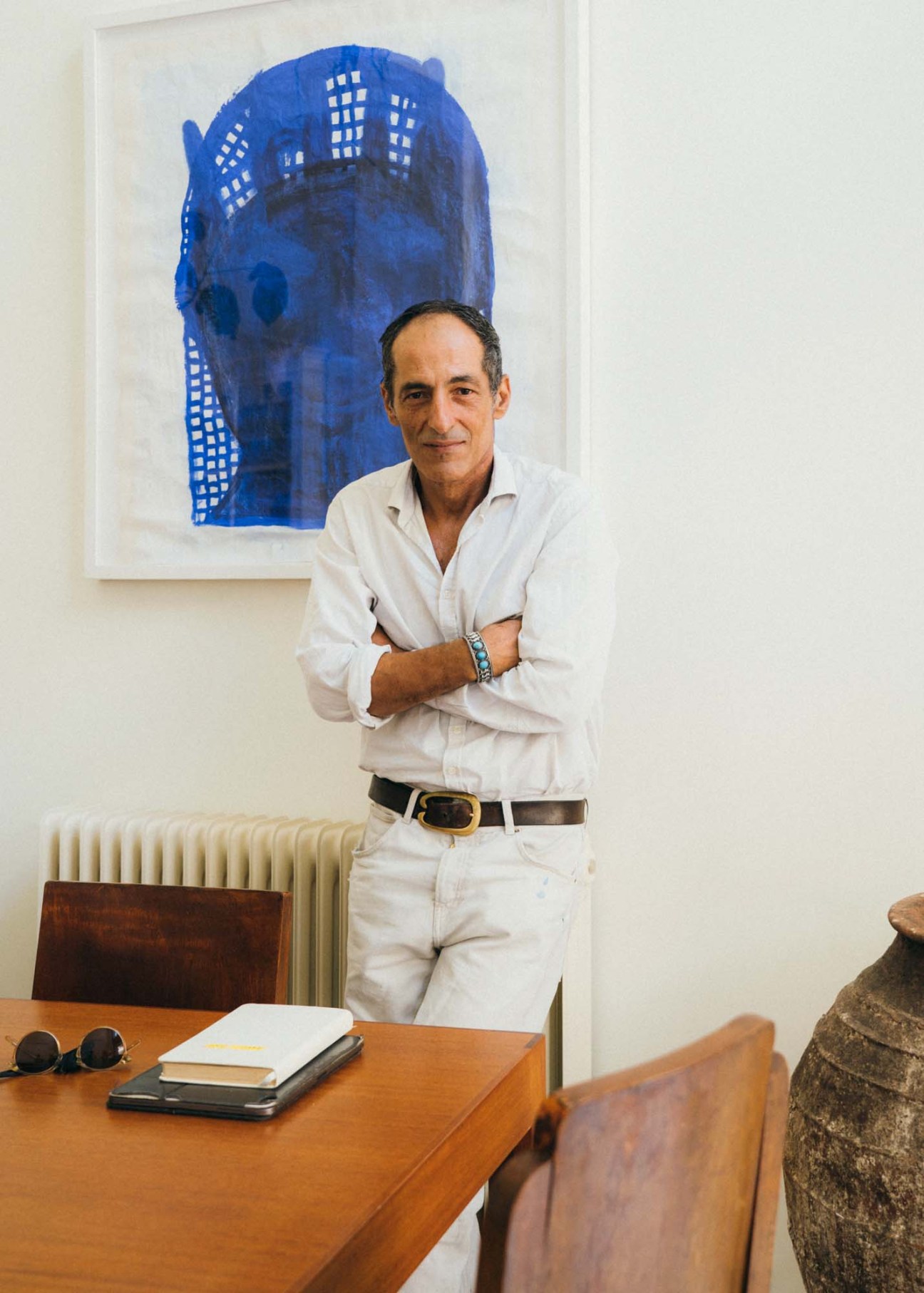 Athenian artist Theodore Psychoyos standing beside his abstract blue ink artwork featuring a building design