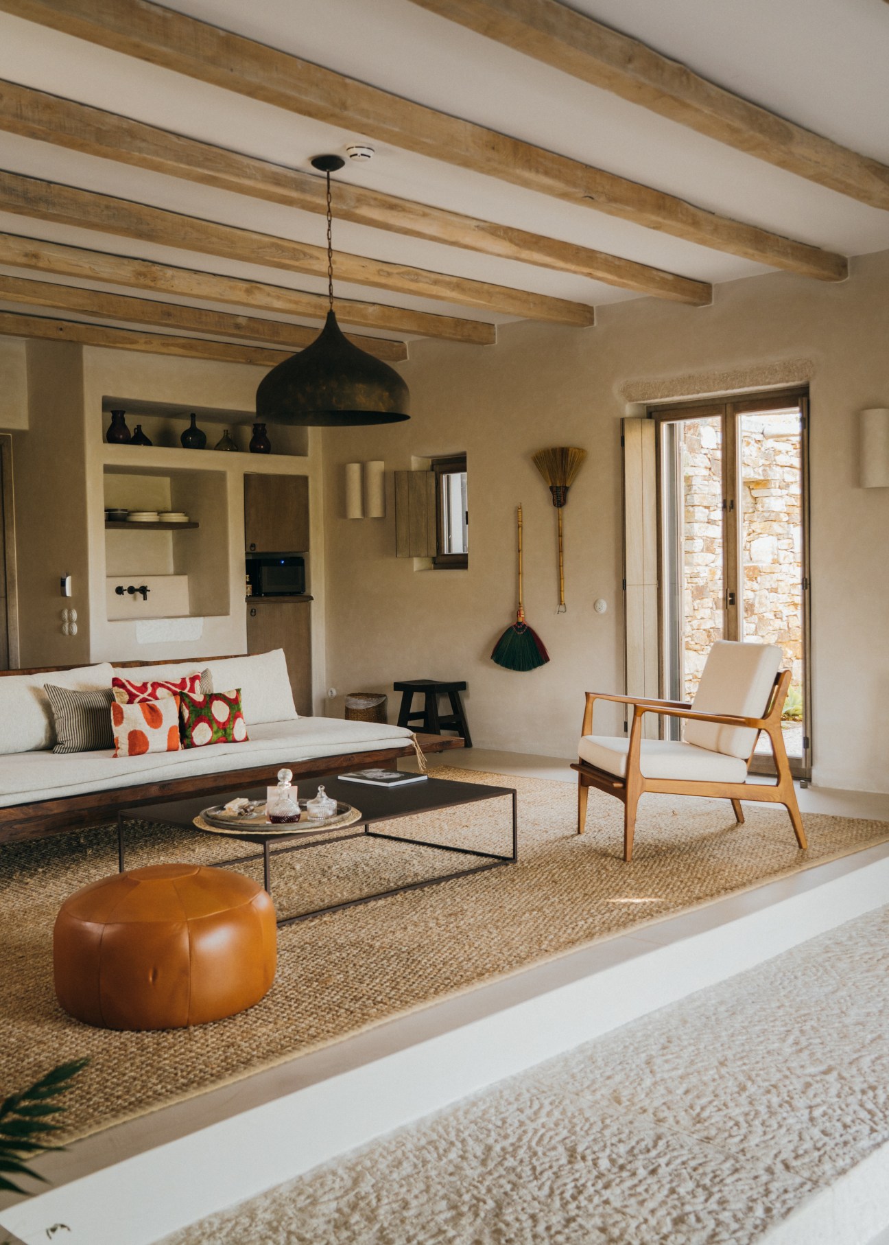 Modern living room with exposed wooden ceiling beams, neutral furniture, and Mediterranean-style architecture