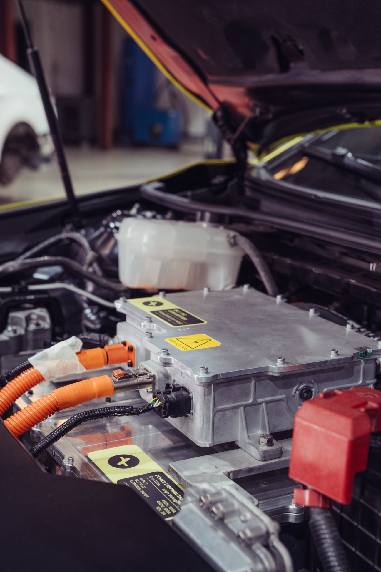 Close-up of Peec's electric battery pack and orange wiring installed under a retrofitted taxi's hood.