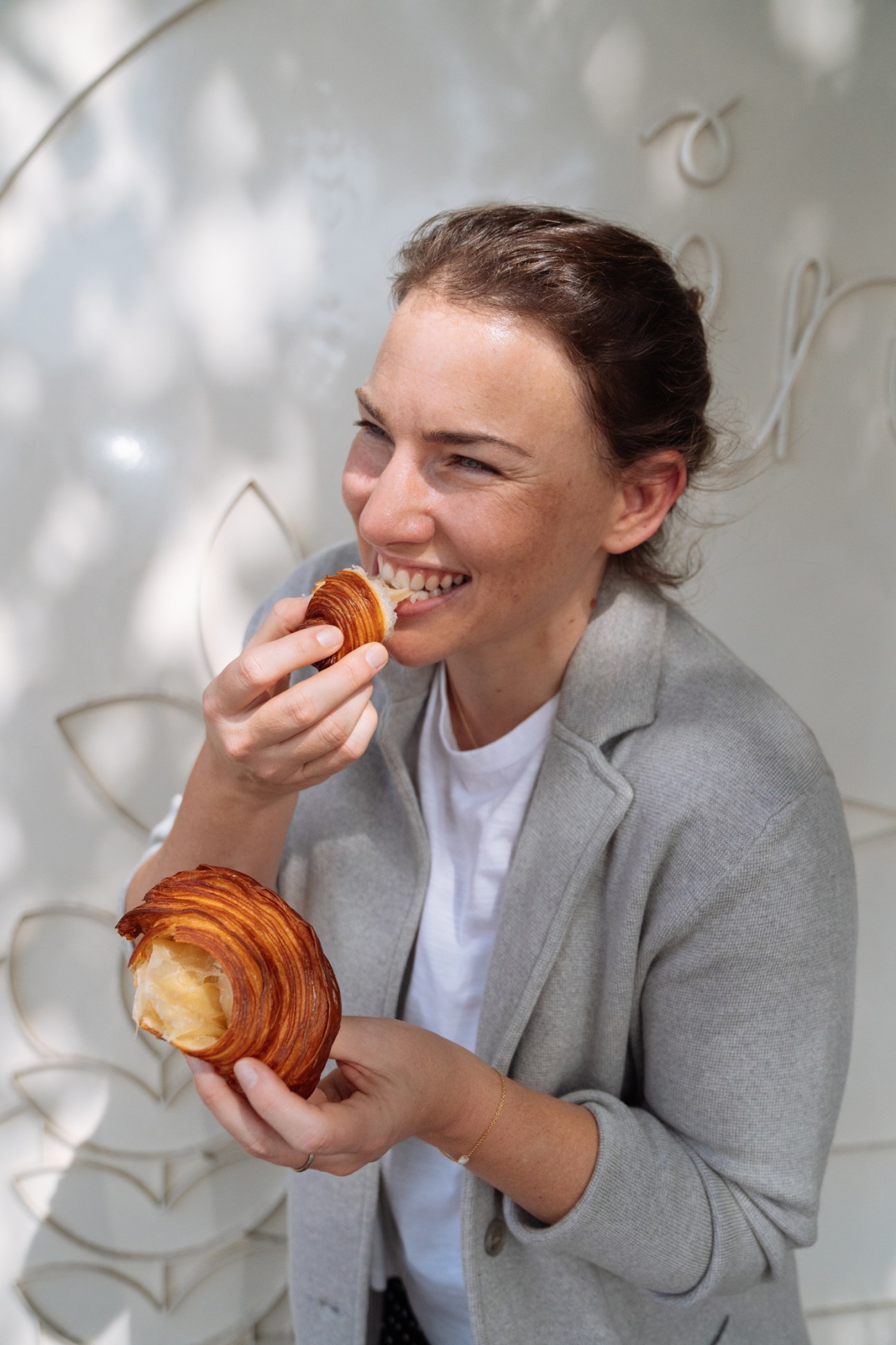 Kathy Johnston, chief chocolate officer at Mirzam, eating a croissant while holding another pastry.