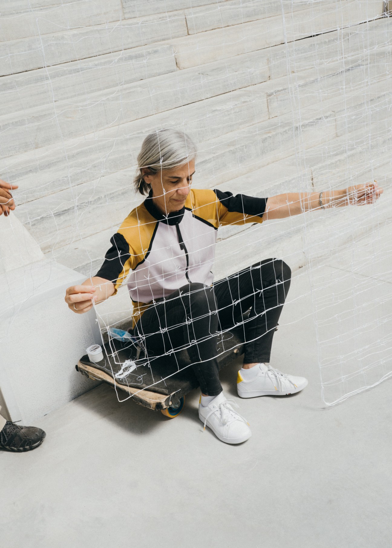 Artist Maria Loizidou displays a delicate white thread installation in a minimalist gallery space.