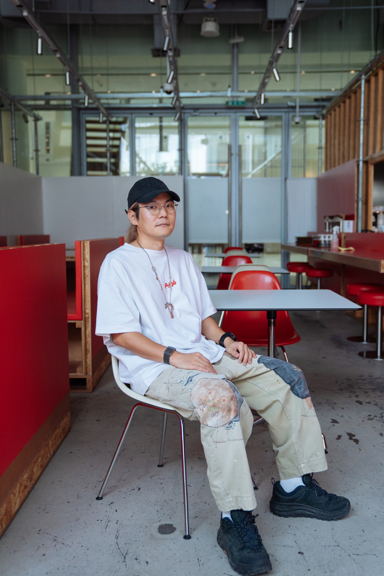 Peter Ahn, founder of Selectshop Frame, sits in a modern retail space with red chairs and glass partitions.
