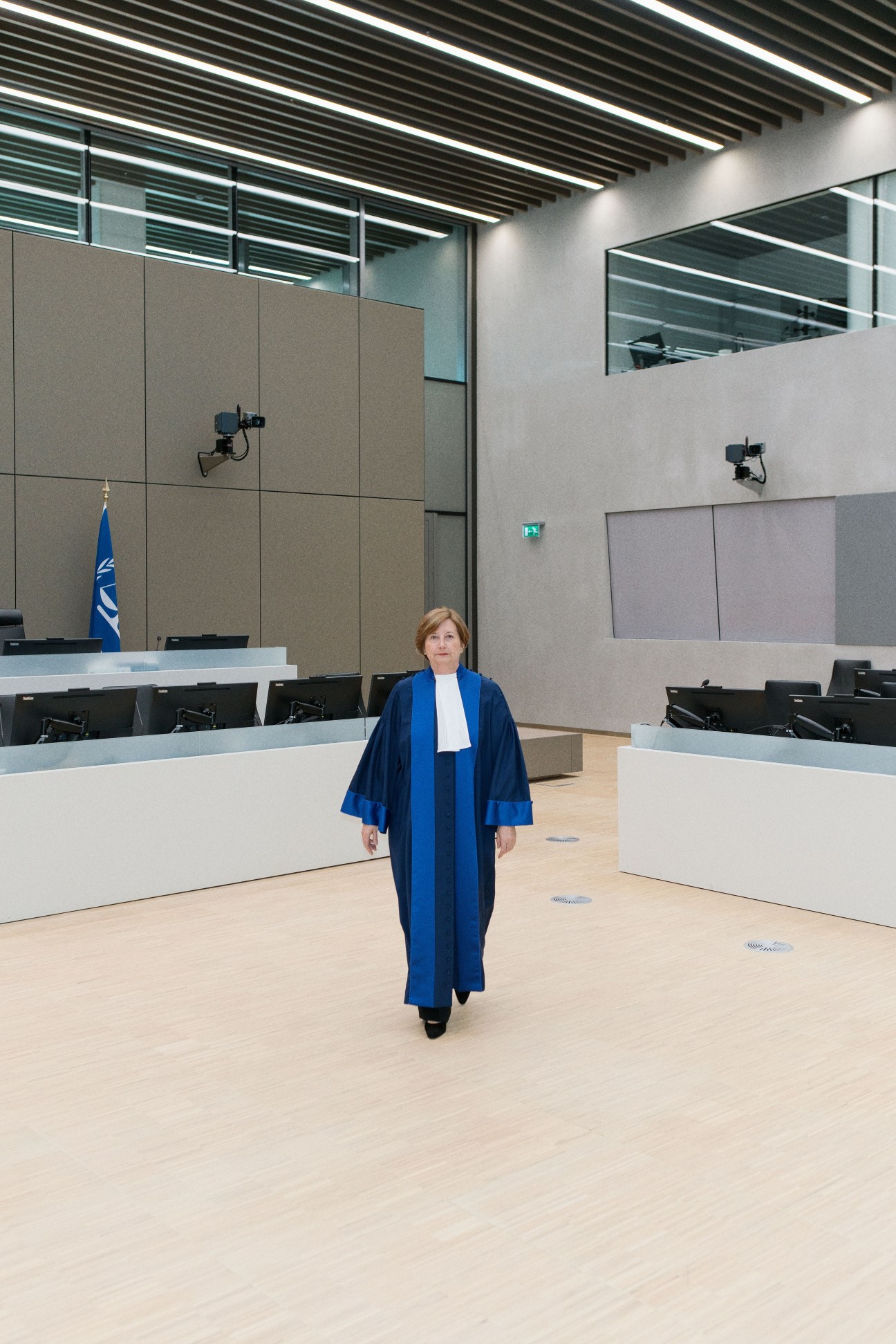 Silvia Fernández de Gurmendi, President of the ICC, stands in a modern courtroom with minimalist design.