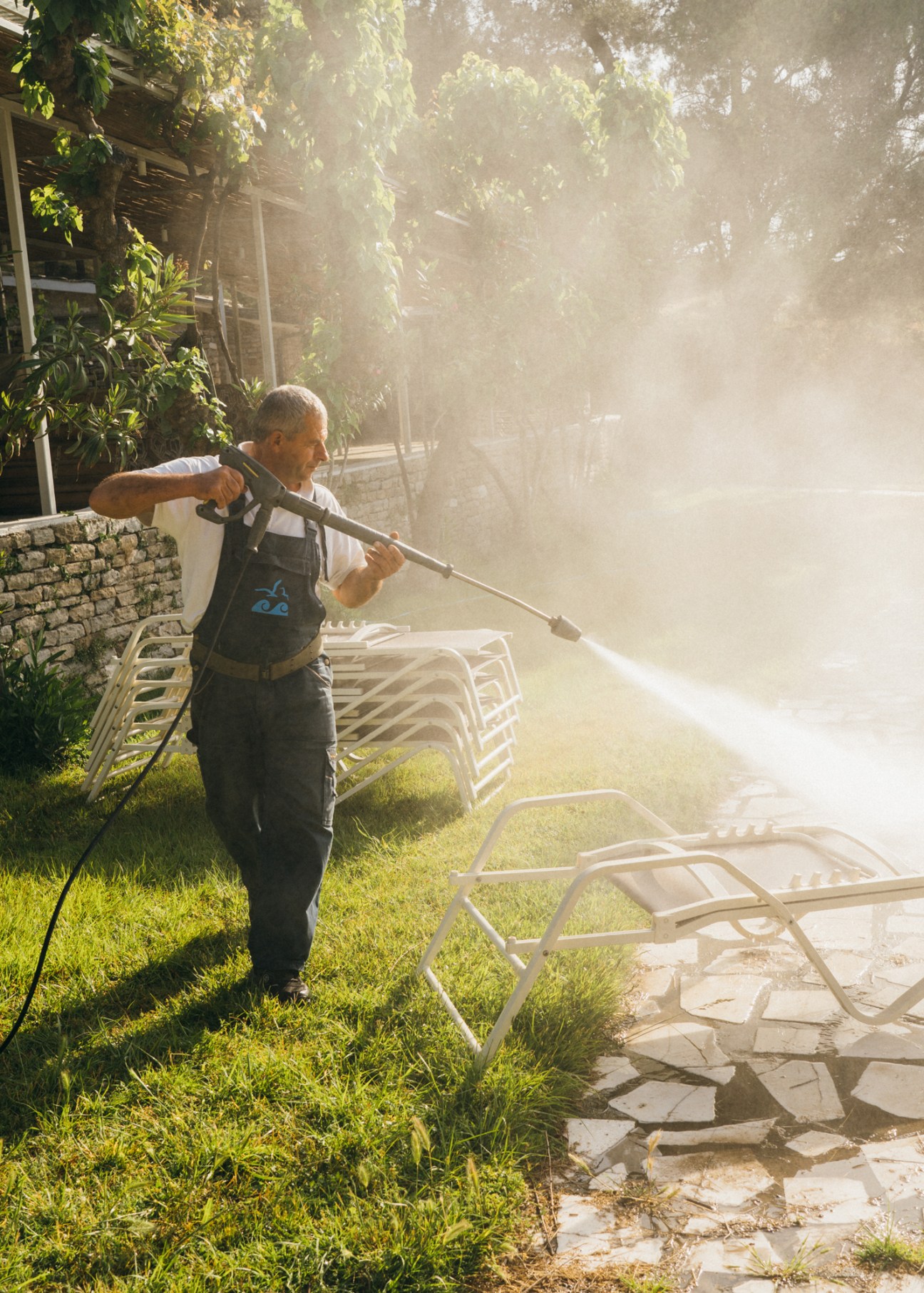 A worker sprays water on beach loungers at Makryammos hotel in preparation for the tourist season.