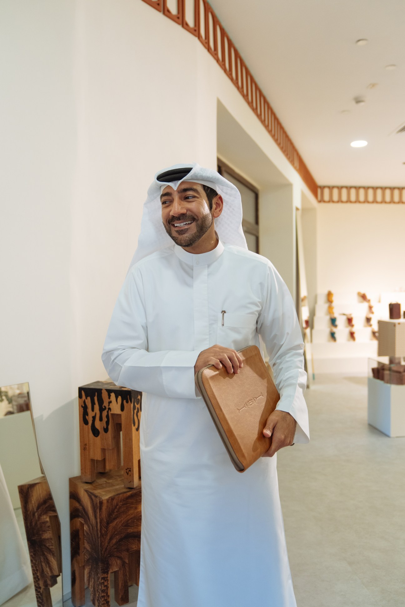Mohammed Kazim holds a tan leather sandal in a modern showroom space.