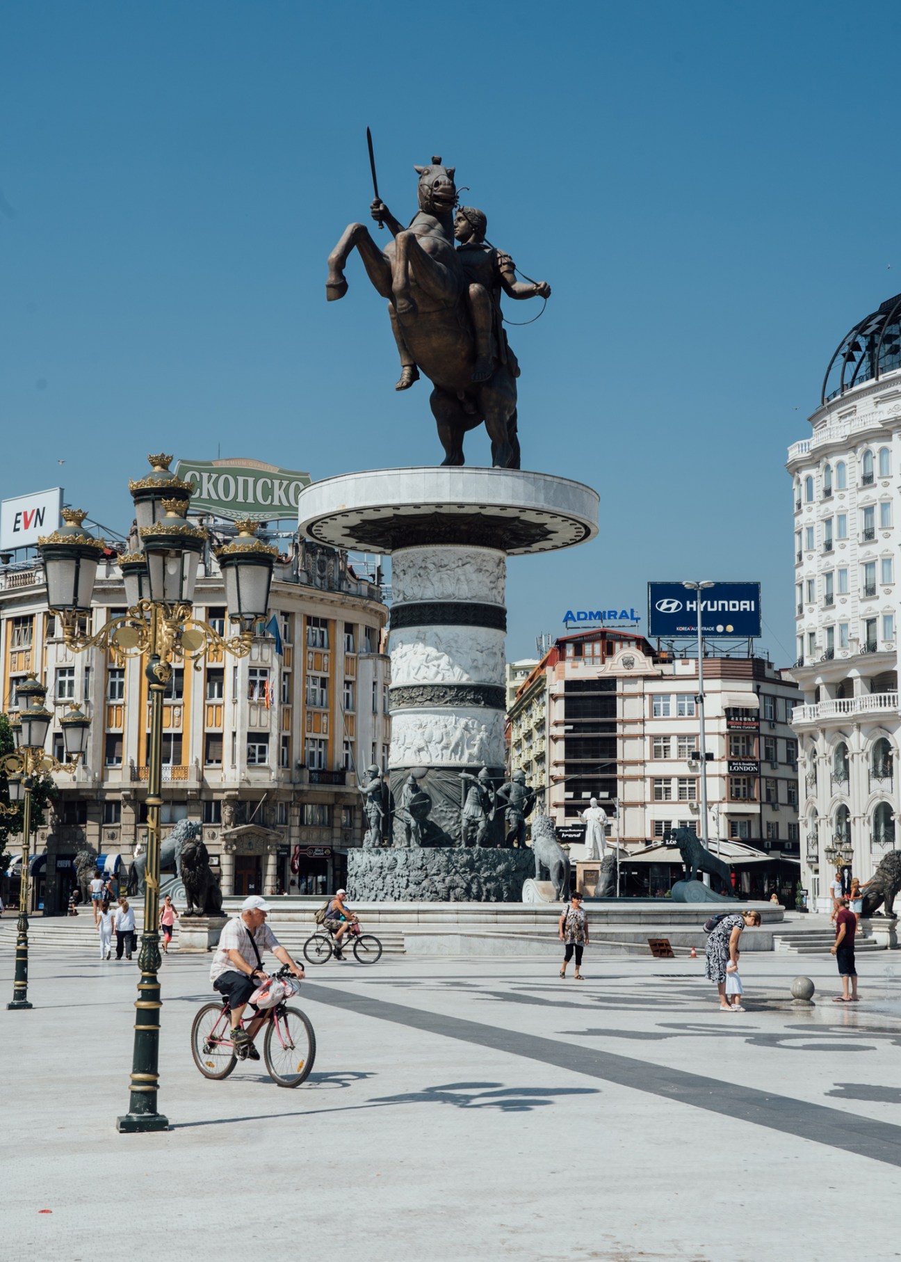 Large statue of warrior on horseback with sword raised, mounted on ornate pedestal in city square