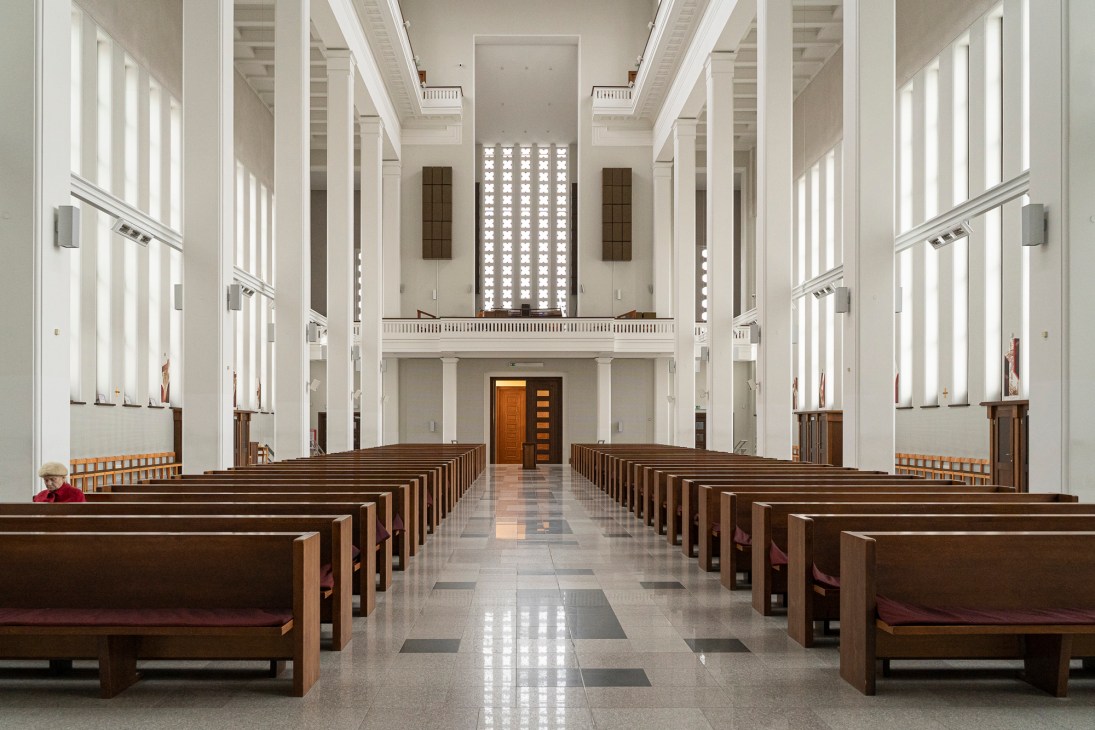 Interior of Christ's Resurrection Church showing rows of wooden pews, white columns and minimalist architecture
