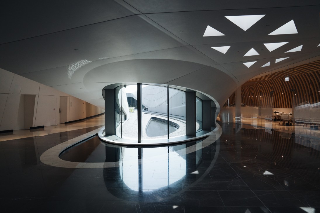 Interior of Beeah HQ showing curved glass reception pod with geometric ceiling skylights and polished floors.