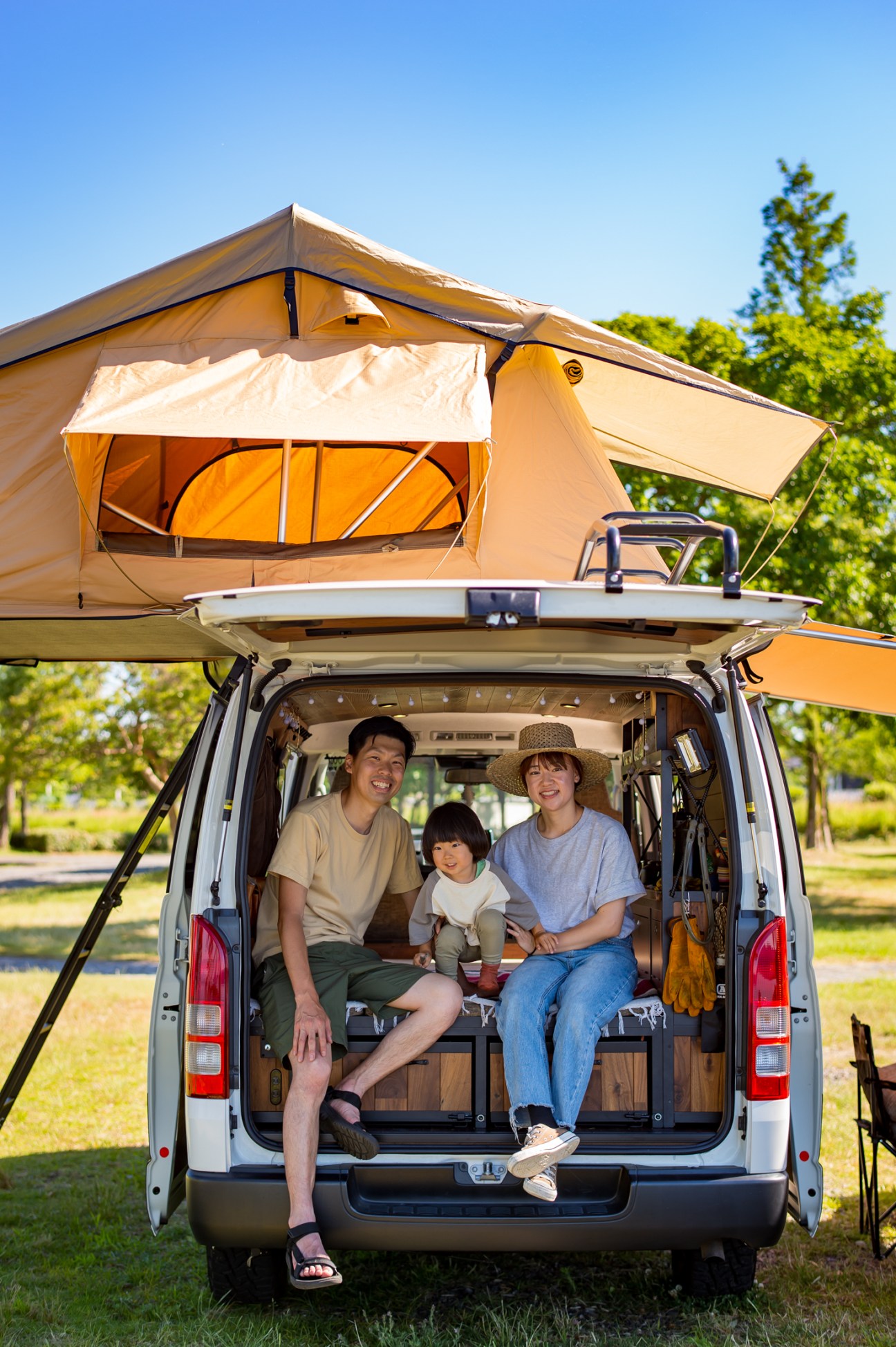 Takahiro Fujita with wife Yuki and son Natsukia sitting in back of van with rooftop tent