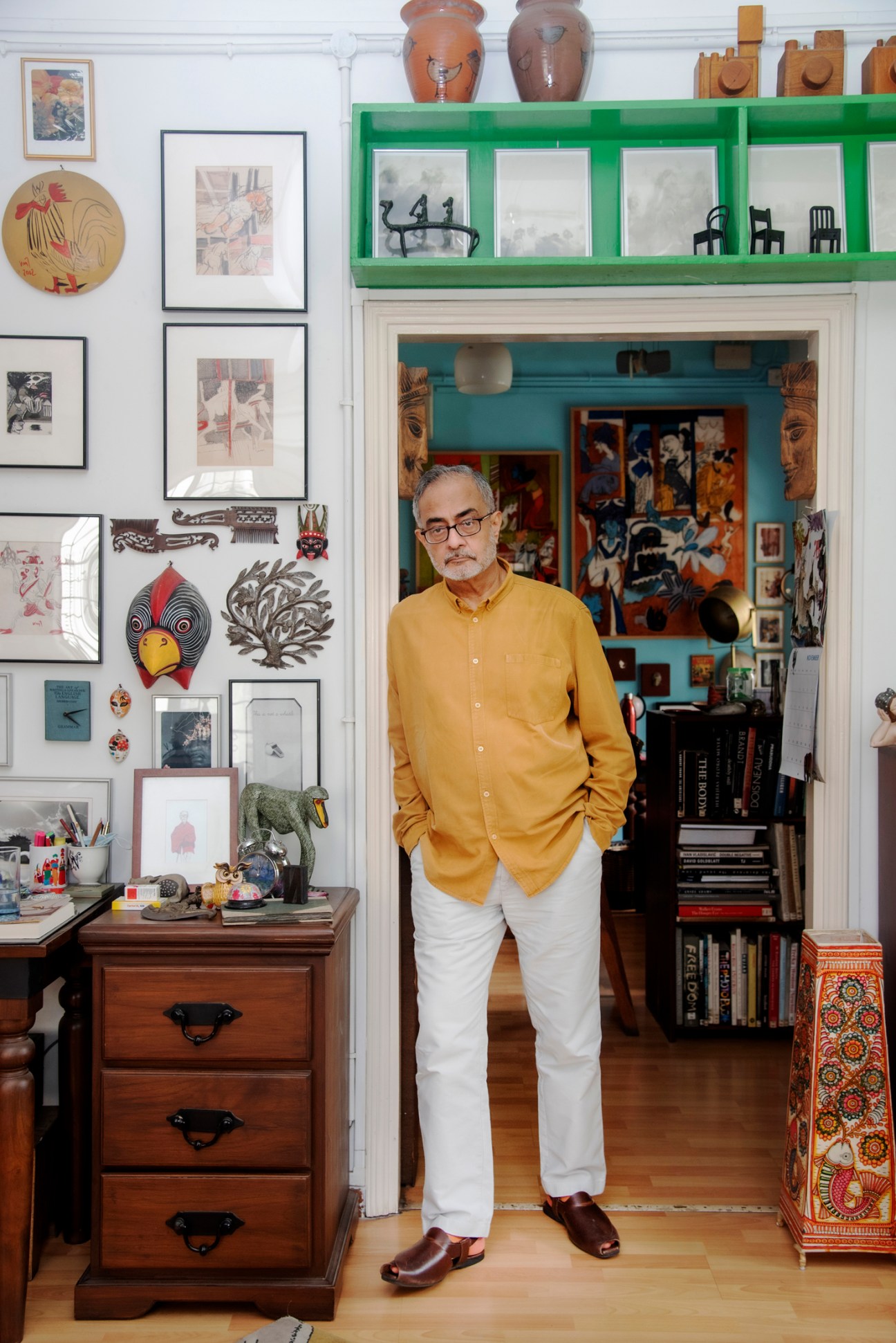 Naveen Kishore of Seagull Books standing in his colorful home-like office space surrounded by books and artwork