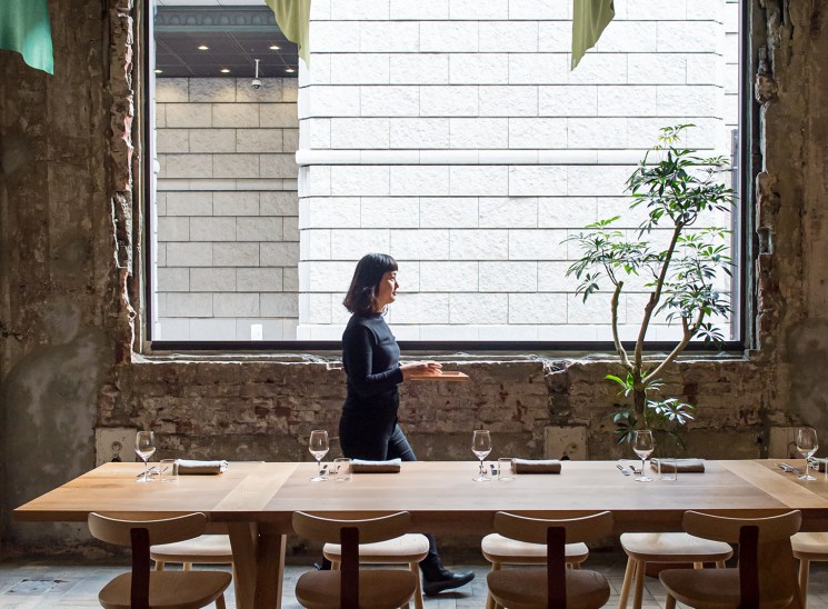 Server walking past a set dining table in a rustic restaurant.