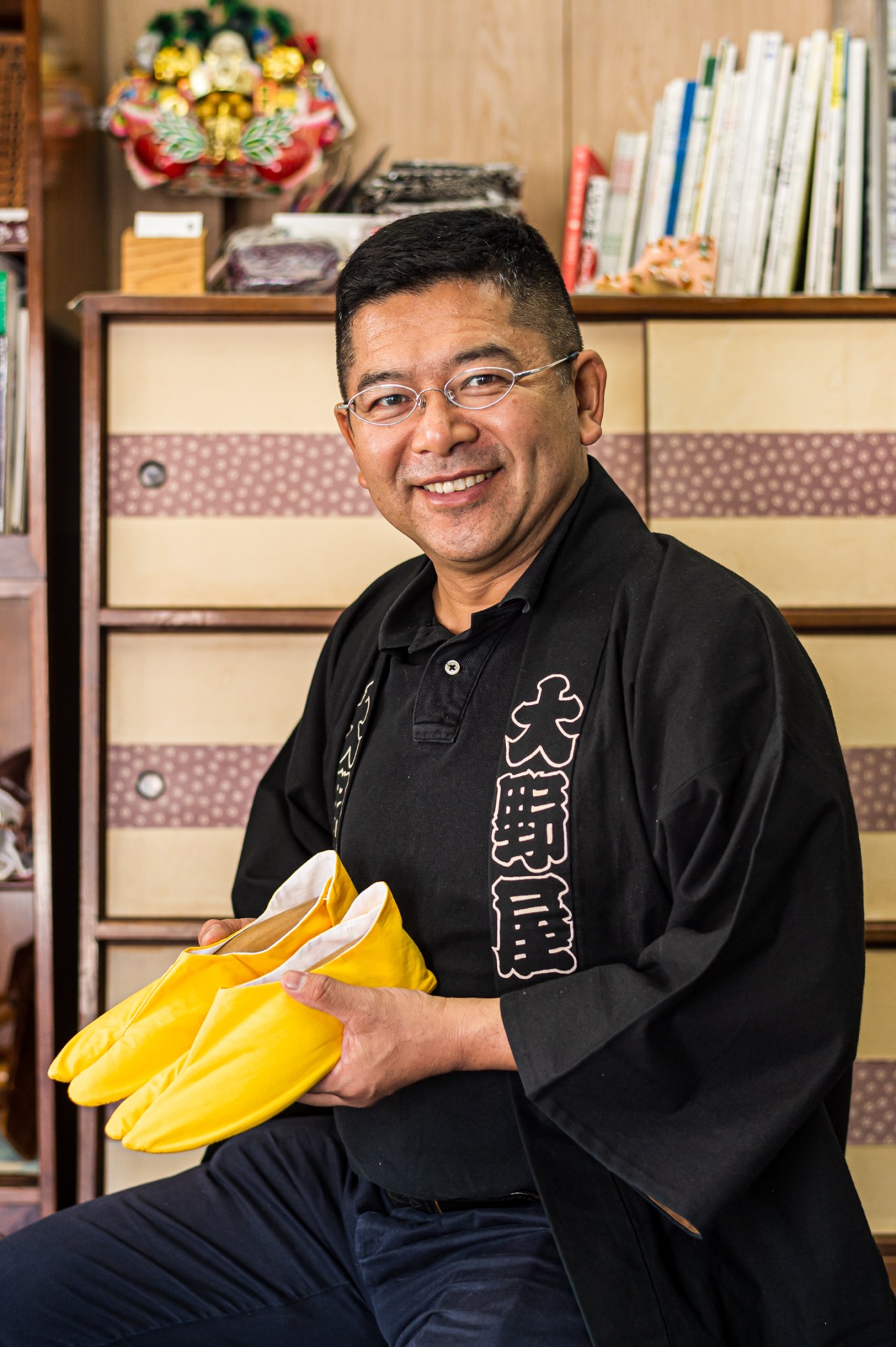 Onoya Sohonten owner Shigeo Fukushima holding yellow tabi socks in his traditional sock shop